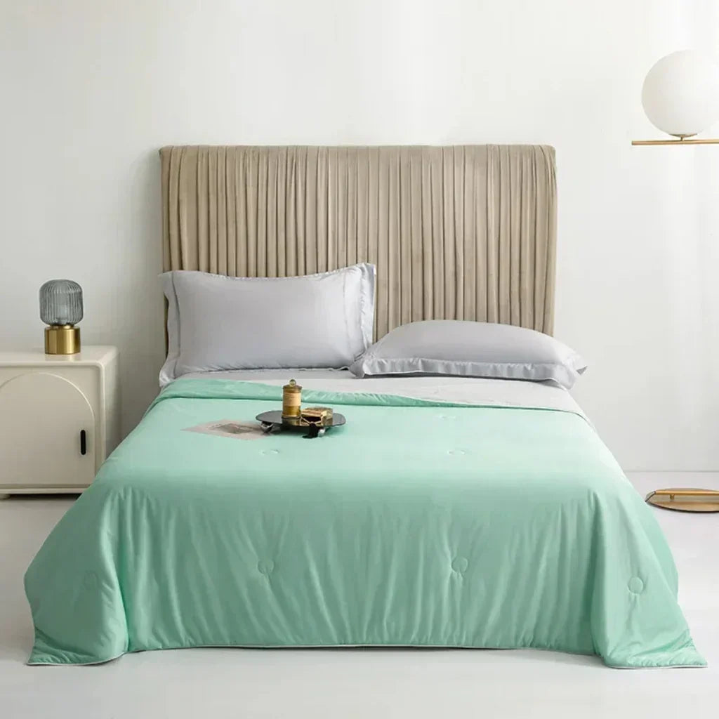 "Kühlende Sommerdecke in Himmelblau auf Bett, ideal für heiße Nächte, atmungsaktiv und hautfreundlich für erholsamen Schlaf."